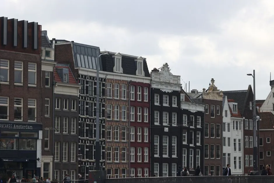 A row of tall, narrow canal houses in central Amsterdam, each with its own distinct gable and entrance