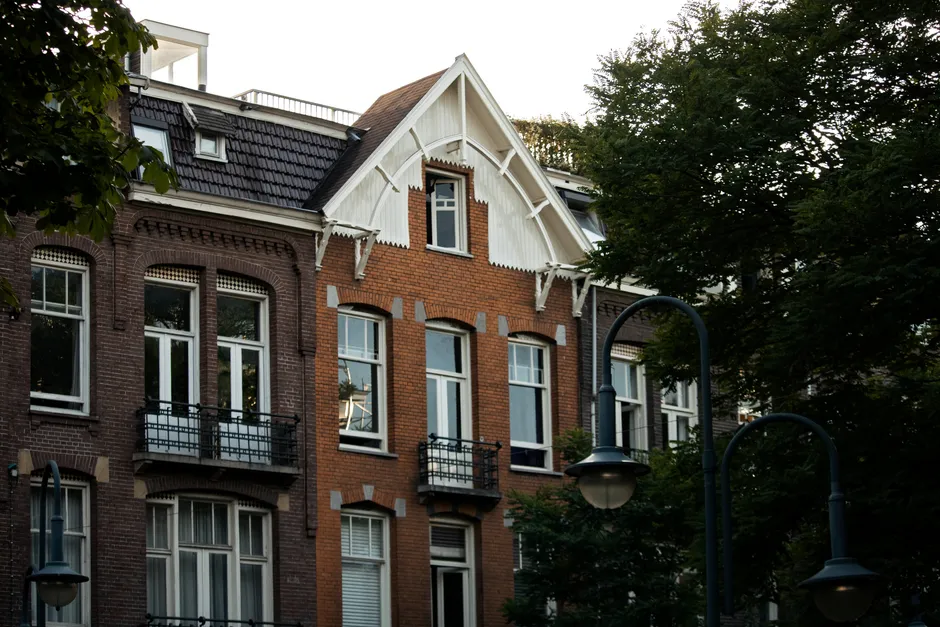 A row of classic Amsterdam townhouse facades with tall windows and gabled rooflines, typical of the older rental stock that gets scored under the WWS points system
