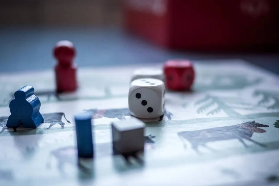 Close-up of colorful wooden board game pieces, dice, and pawns scattered across an illustrated game board