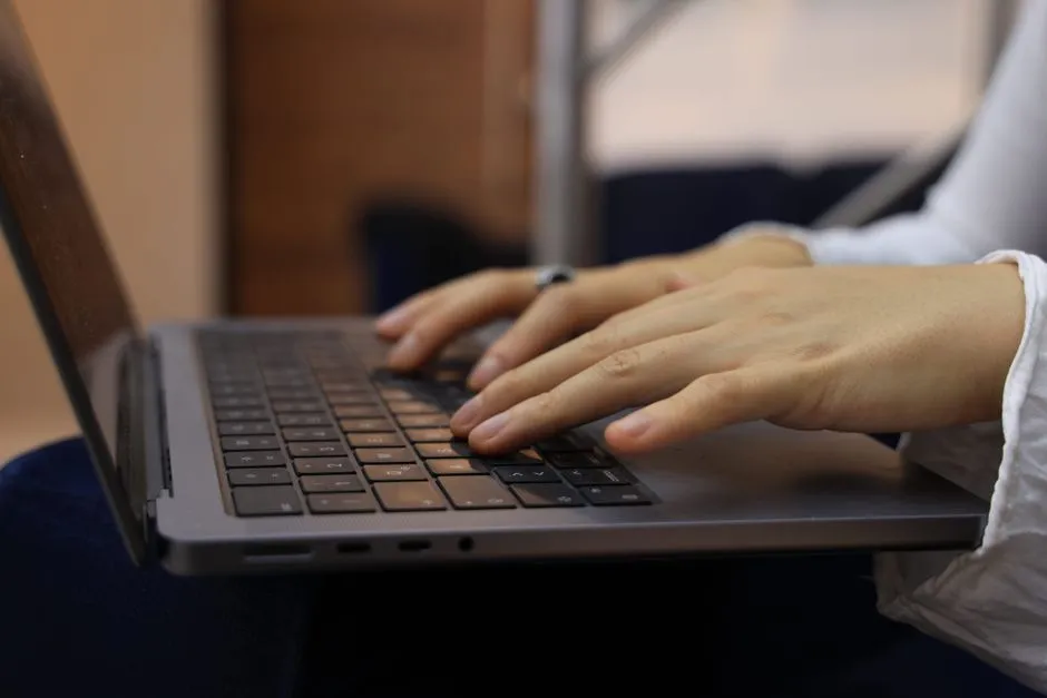 Close-up of two hands typing on a laptop keyboard, no face or screen content visible