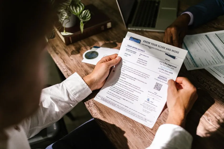 Two people at a desk reviewing a printed credit offer document together, one holding the page and pointing at a line item
