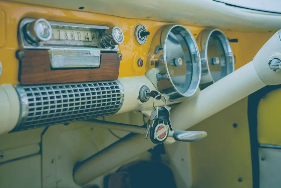 Hardal sarısı bir vintage araba göstergesi, kontak anahtarında asılı bir anahtar seti, yüz ya da okunabilir kişisel belge görünmüyor