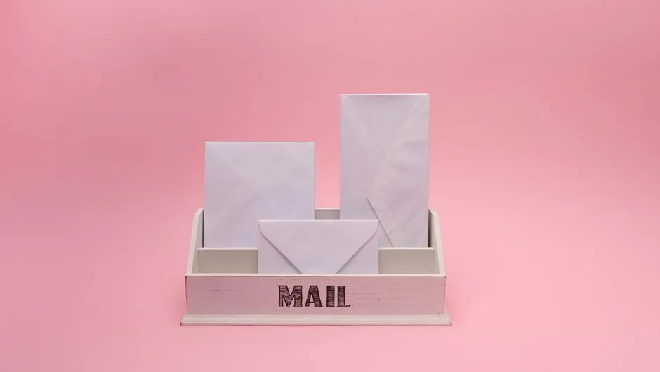Rows of white envelopes sorted into the pigeonholes of a mail organizer, no readable addresses visible