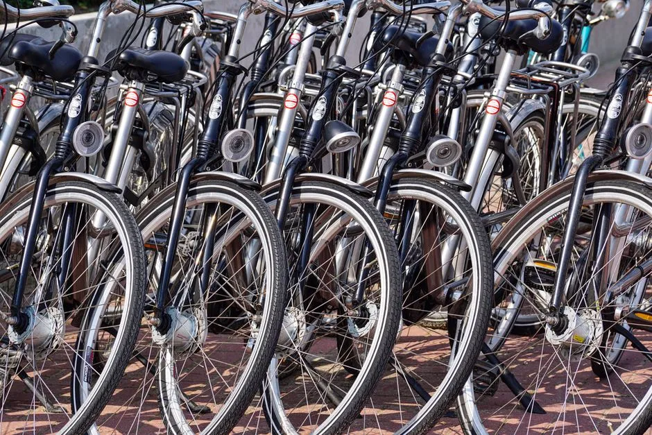 A tightly packed row of city bicycles parked side by side, seen from the front wheel, no people, faces, or readable logos visible