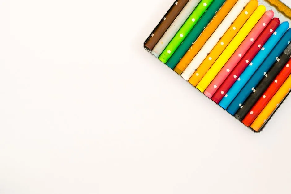 A tin case of colorful wooden pencils and crayons in a row, arranged diagonally on a plain white background, no people, text, or logos visible