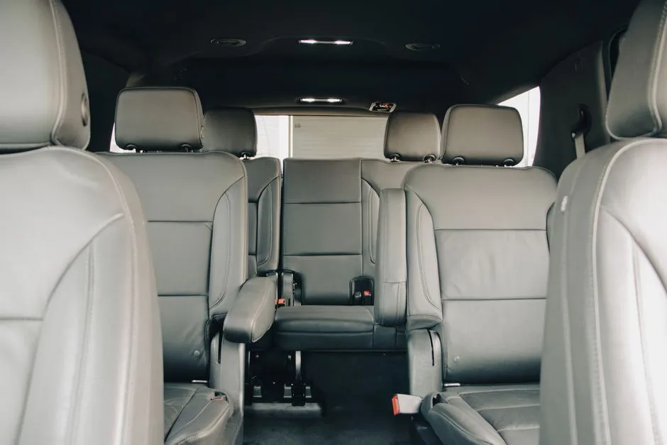 Empty gray leather rear passenger seats inside a modern van or SUV, seen from the middle row looking toward the back, no people, no readable text or logos visible
