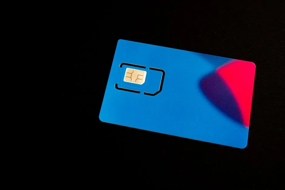 A blue prepaid SIM card resting on a dark surface with its gold contact chip visible