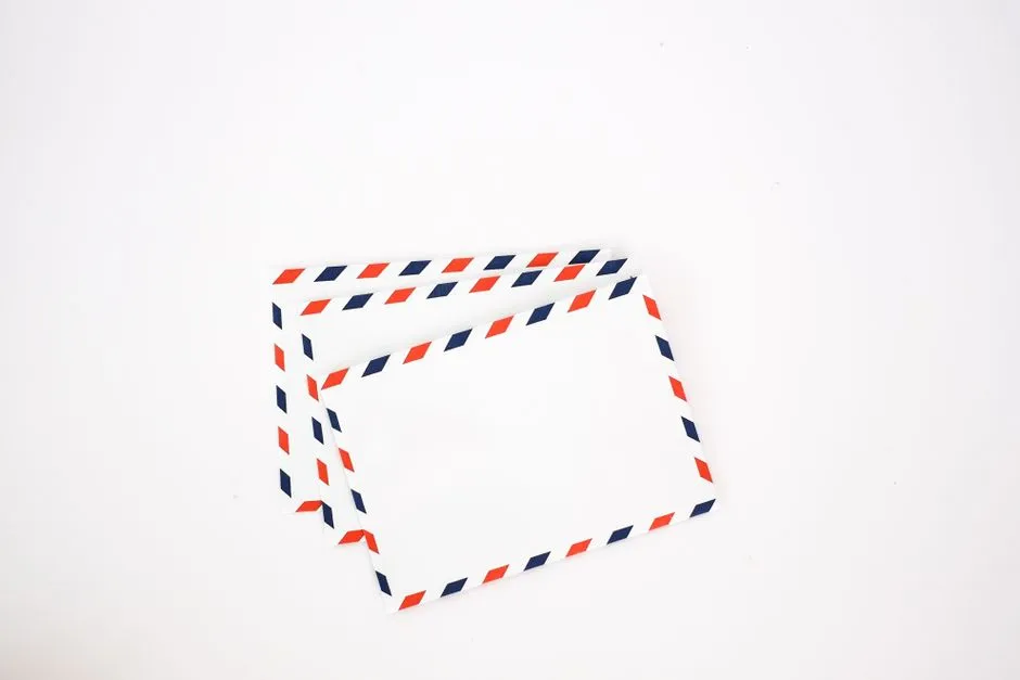 Two plain white envelopes with a red and blue striped airmail border, stacked on a plain background, no visible text or people