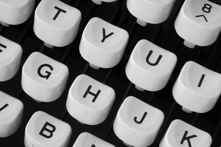 Close-up of vintage typewriter keys arranged in overlapping diagonal rows, each round white keycap showing a single black letter