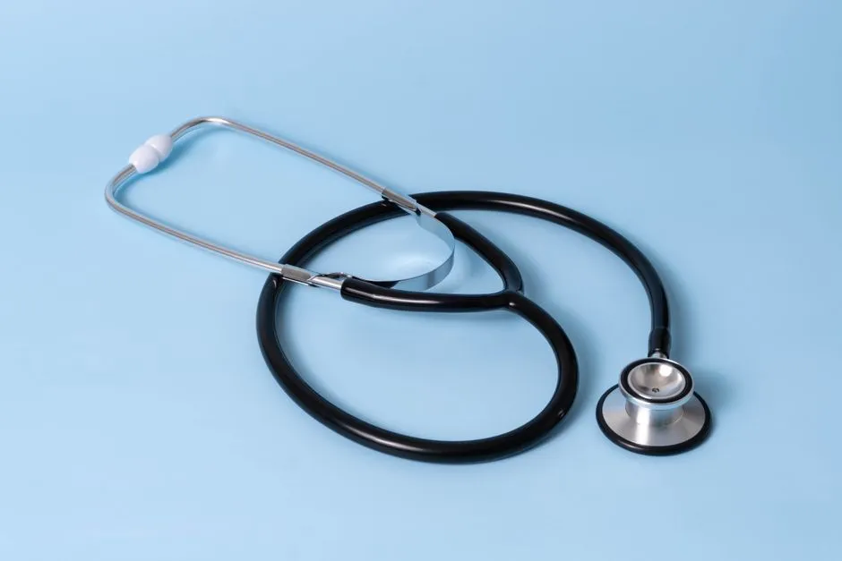 A black stethoscope coiled on a light blue background