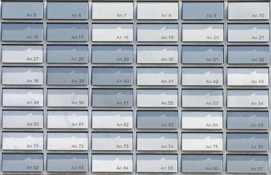 A symmetrical grid of numbered apartment building mailboxes with narrow mail slots