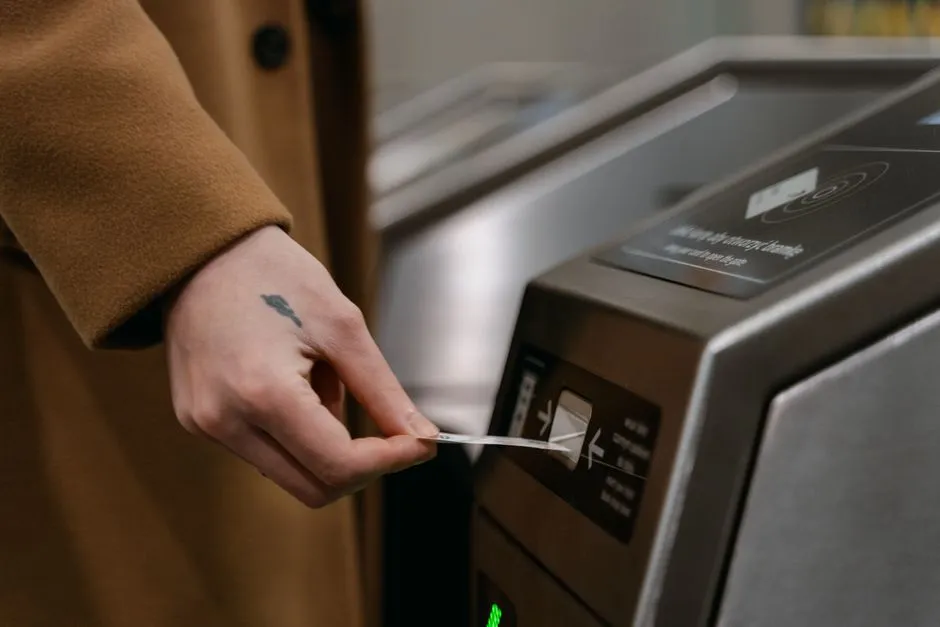 A hand inserting a paper ticket into a transit fare gate reader