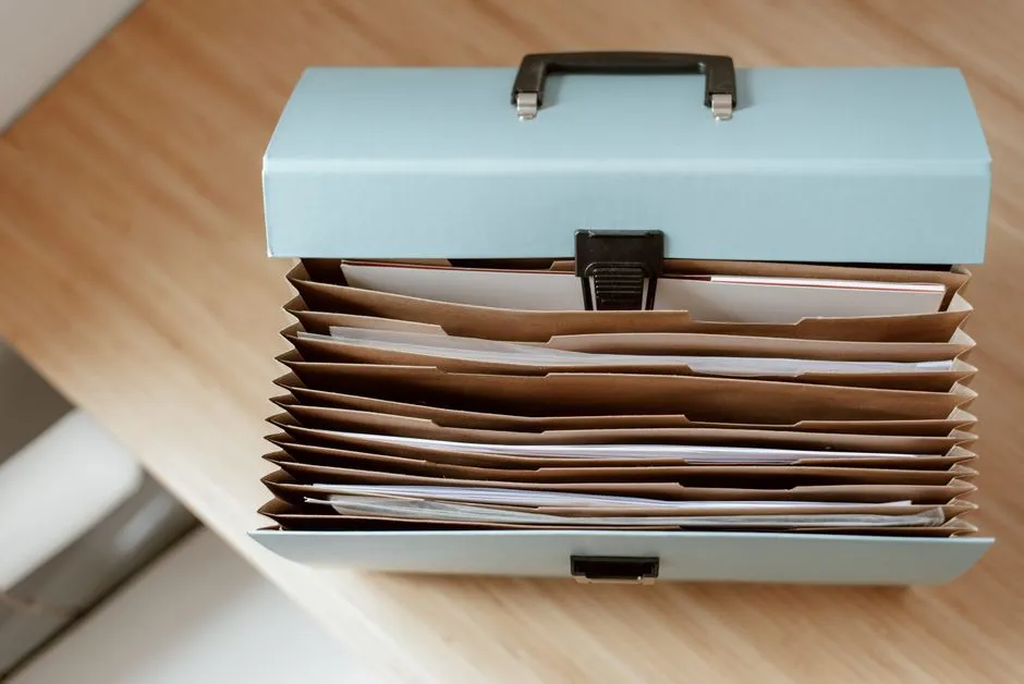 An open accordion document folder full of paper files on a wooden desk