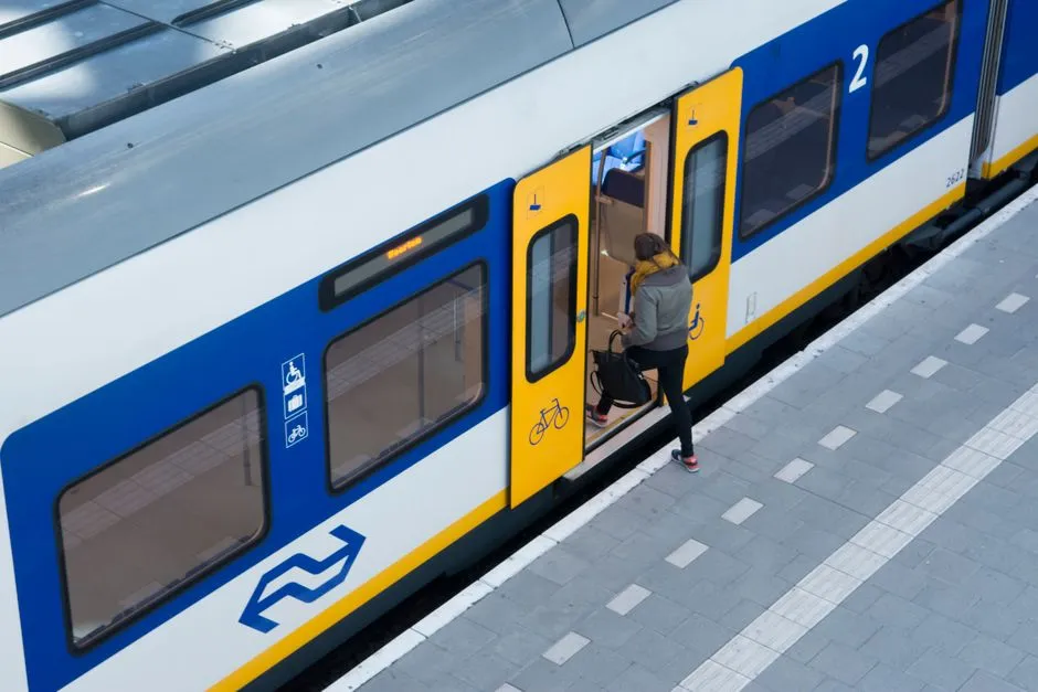 A passenger boarding a regional train through an open door on a platform