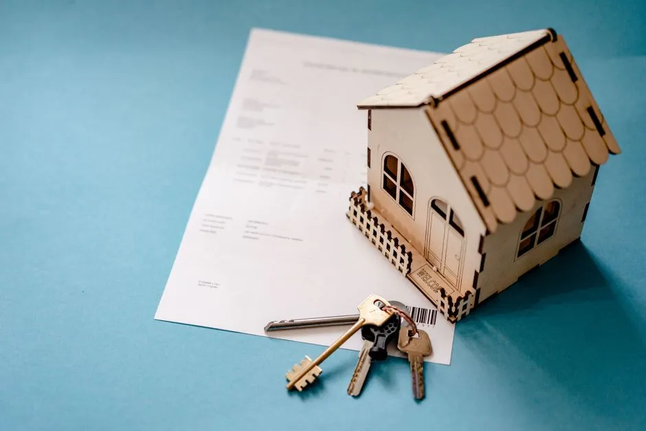 A small model house and a set of keys resting on top of a signed rental agreement document