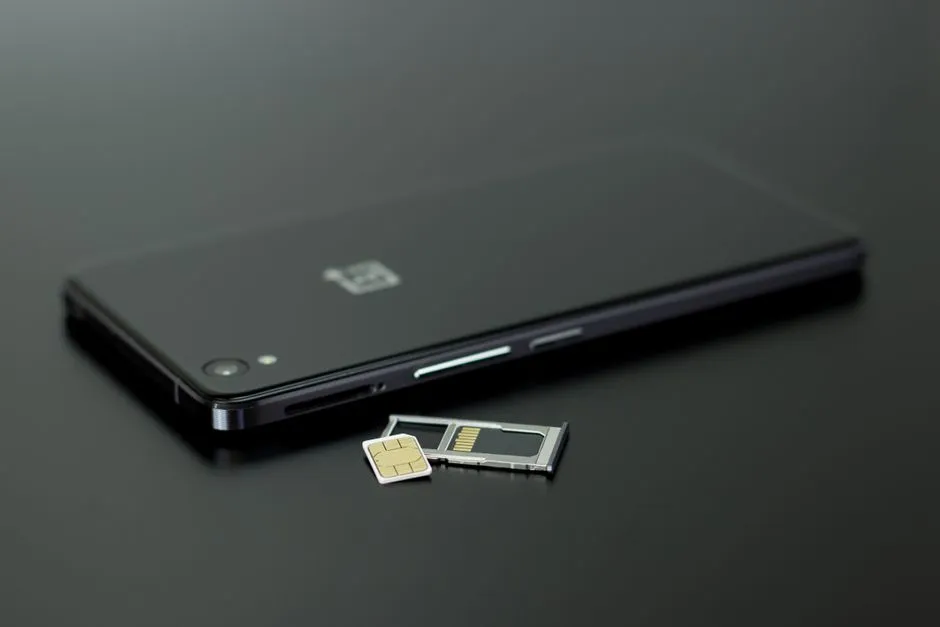 A SIM card and its ejected tray resting next to a smartphone
