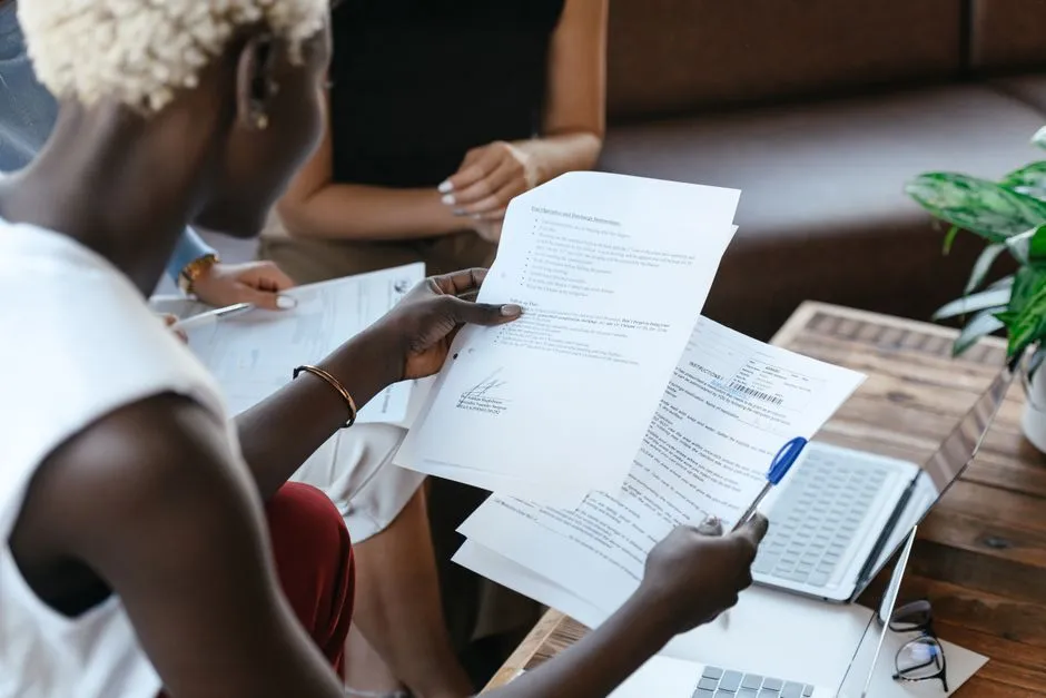Someone comparing several printed policy documents side by side with a pen in hand